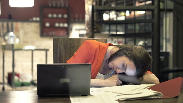 Tired businesswoman sleeping on table in kitchen at night 