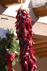 Naklejka premium Chile Ristra hands beside a Christmas wreath in Santa Fe, New Mexico
