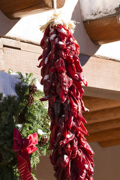 Chile Ristra hands beside a Christmas wreath in Santa Fe, New Mexico