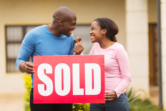 excited black couple holding sold sign