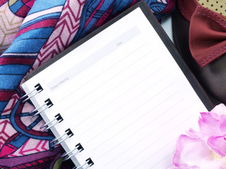 blank notepad pen and flowers over white wooden background top view with copy space