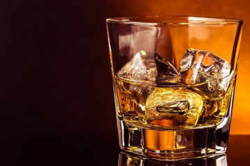 glass of whiskey on black table with reflection, warm atmosphere