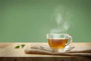 Wall murals Tea Cup of tea with sacking on the wooden table and green background