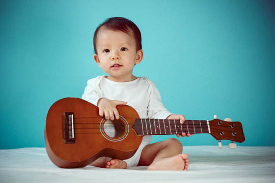 Baby girl playing ukulele (soft focus on the eyes)