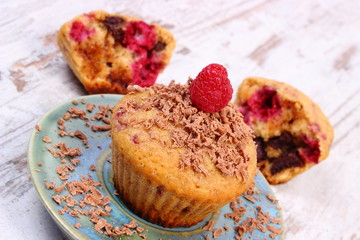 Baked muffins with raspberries and grated chocolate on wooden background, delicious dessert