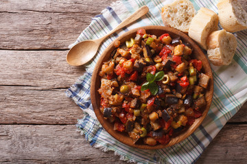 Caponata with aubergines in a wooden plate. Horizontal top view
