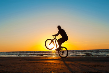 Fototapeta na wymiar Man cyclist silhouette on blue sky and multicolored sunset backg