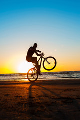 Man cyclist silhouette on blue sky and multicolored sunset backg