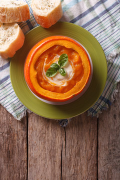 soup with sour cream and basil in a baked pumpkin. vertical top view
