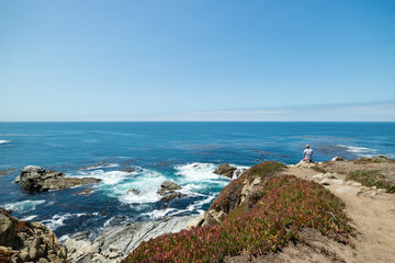 Man sitting and contemplating with beautiful coastal view on a clear blue summers day, Pacific Coast Highway, United States