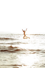 Fototapeta na wymiar Flying through the waves. Happy girl jumping in the sea.