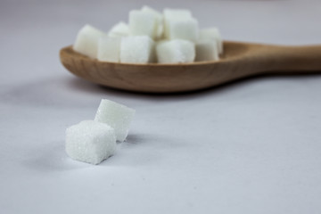 Sugar Cubes on Spoon on Isolated White Background with Harsh Shadow, which can be used to imply dark side of Sugar