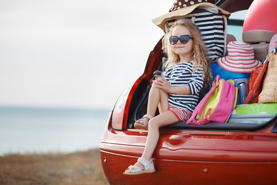 Portrait of a little girl sitting in the trunk of a car