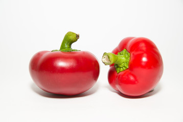 Two ripe red peppers on over white