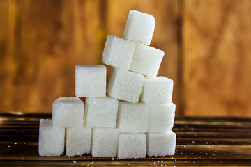 Pile of Sugar Cubes Stacking on Table over Wooden Background