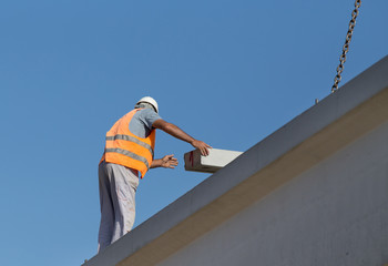 Height worker placing truss on building skeleton