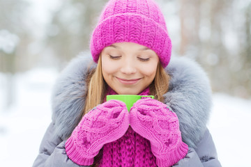 smiling young woman with cup in winter forest