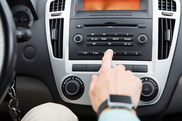 Fototapeta na wymiar close up of male hand turning on radio in car