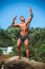 Obraz premium Man Athlete stands on a rock by the sea against the sky