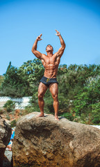 Man Athlete stands on a rock by the sea against the sky