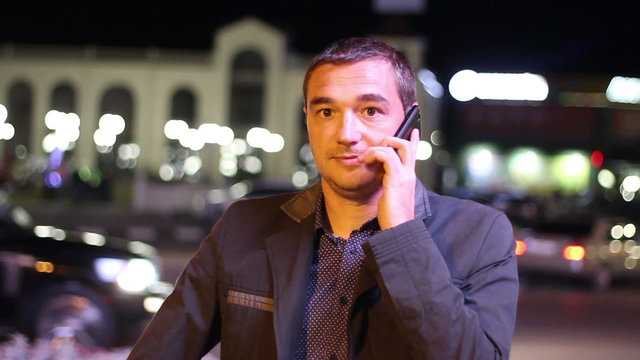 Smart phone man calling on mobile phone at night in city