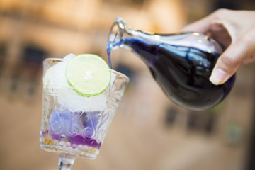 woman's hand pouring pea flower water into a glass