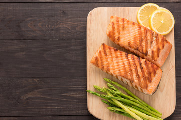 Grilled salmon and lemon, asparagus on the wooden background
