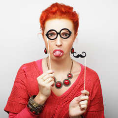 young woman holding mustache and glasses on a stick. 