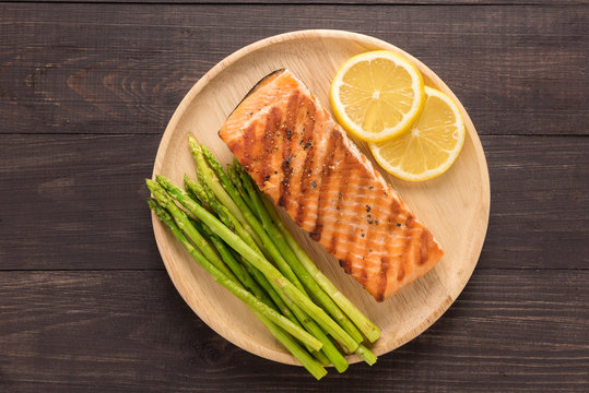Grilled salmon with lemon, asparagus on the wooden background