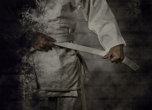  Karateka tying the white belt (obi) with grunge background
