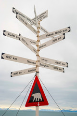 Sign with city distances and polar bear warning, Svalbard, Norwa © dinozzaver