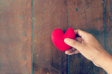 Hand picking  heart on the old wooden background