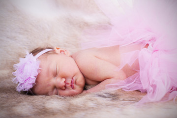 New born baby wearing a pink head band and tutu. 