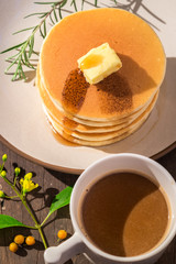 Stack of delicious pancake topped with butter and maple syrup wi
