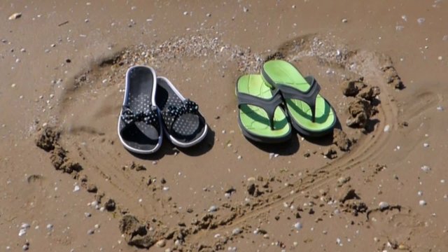 Male and female summer shoes in drawn in the sand heart