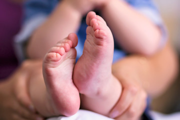 Pies descalzos de bebe en las manos de la madre
