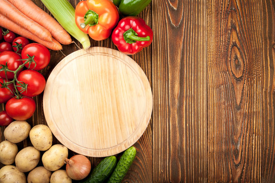 Fresh ripe raw vegetables on wooden cutting board Stock Photo by ratmaner