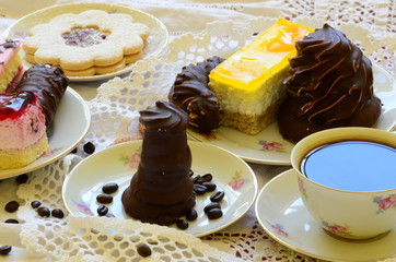 Desserts with cup of coffee, coffee beans and almonds on white tablecloth