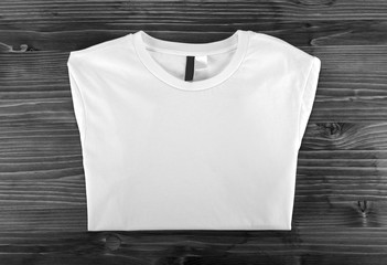 White folded t-shirt template on a wooden background.