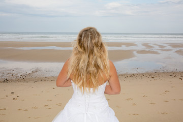 Fototapeta na wymiar Blond and sexy woman at the beach with a wedding dress
