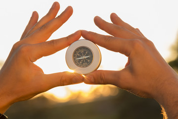 Fototapeta na wymiar Hands holding a compass at sunset