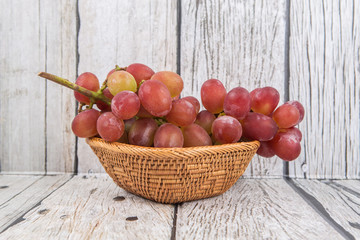 A bunch of fresh red grapes over wooden background