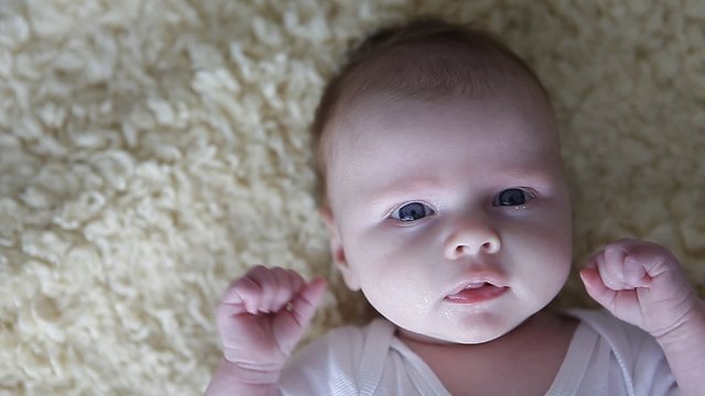 little baby on a blanket smiling and struggle