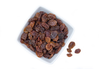 Raisins in square bowl on a white background top view