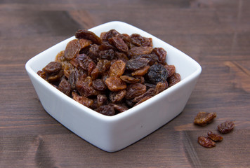 Raisins in square bowl on wooden table