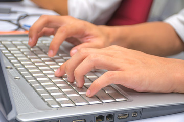 A Man hand typing some work on a laptop keyboard