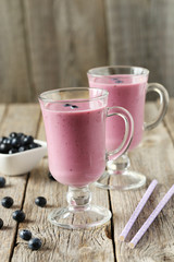 Fresh blueberry smoothie in the glasses on grey wooden backgroun
