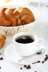 Delicious croissants with cup of coffee on white wooden backgrou