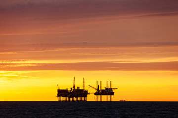 Obraz premium Silhouette of oil platform at sunset