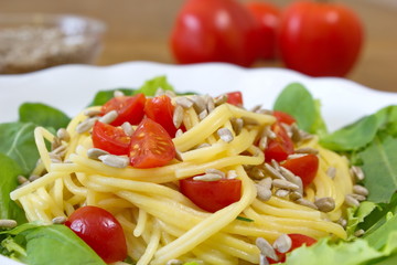 corn spaghetti with tomatoes and sunflower seeds served with salad
